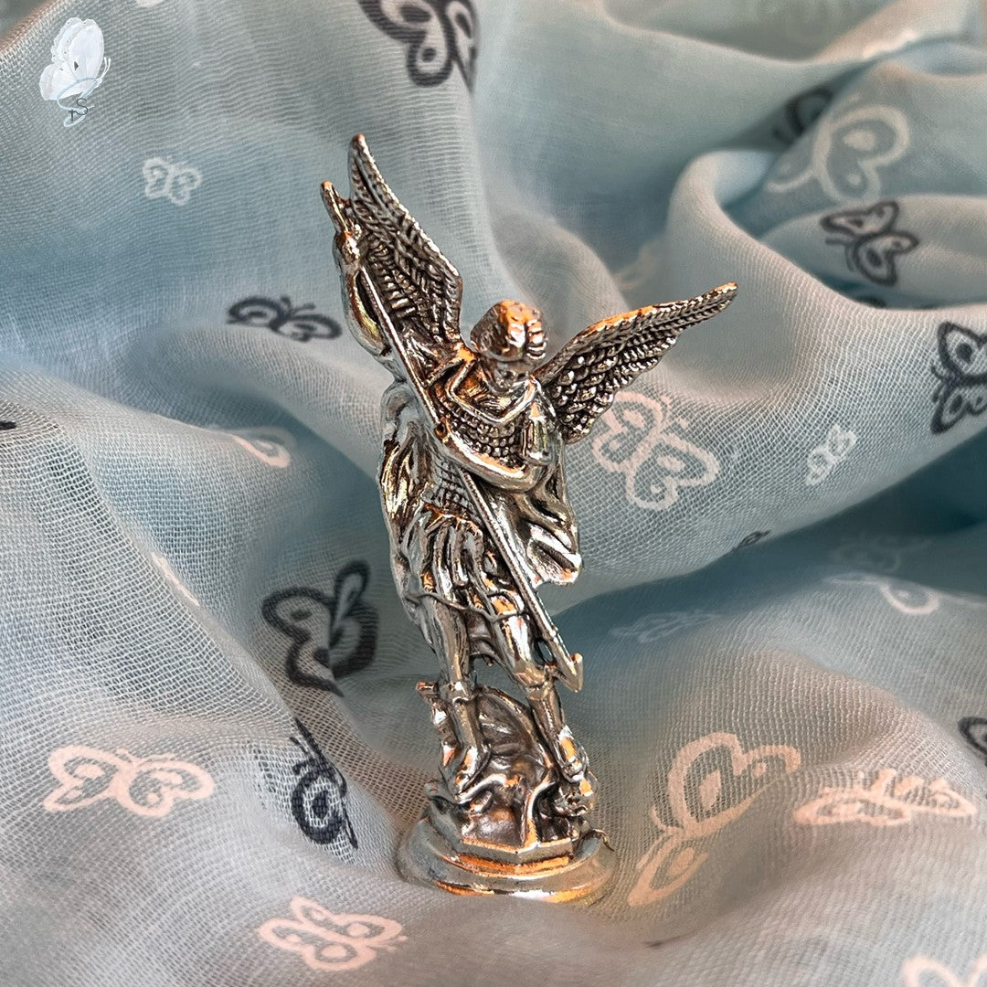 Silver angel figurine on a light blue fabric background